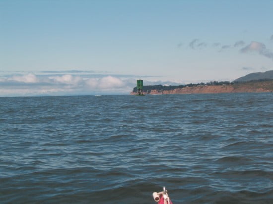 Range using a green buoy in the foreground against a point of land in the background.