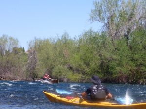 Tom navigates the rapid in his canoe while John looks on